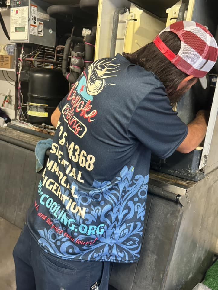 A man wearing a hat and a t-shirt is working on a machine.