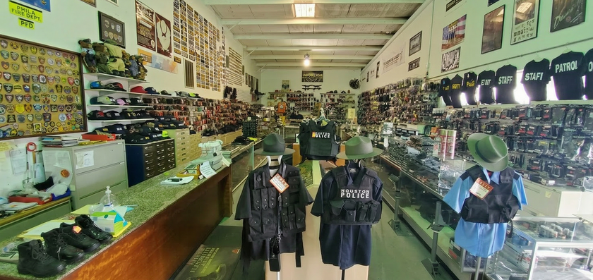 An indoor view of a military surplus store with gear, hats, and uniforms displayed on racks and mannequins.