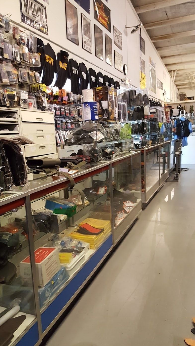 A long indoor view of a retail shop with glass display counters, merchandise on shelves, and clothing hanging on the wall.