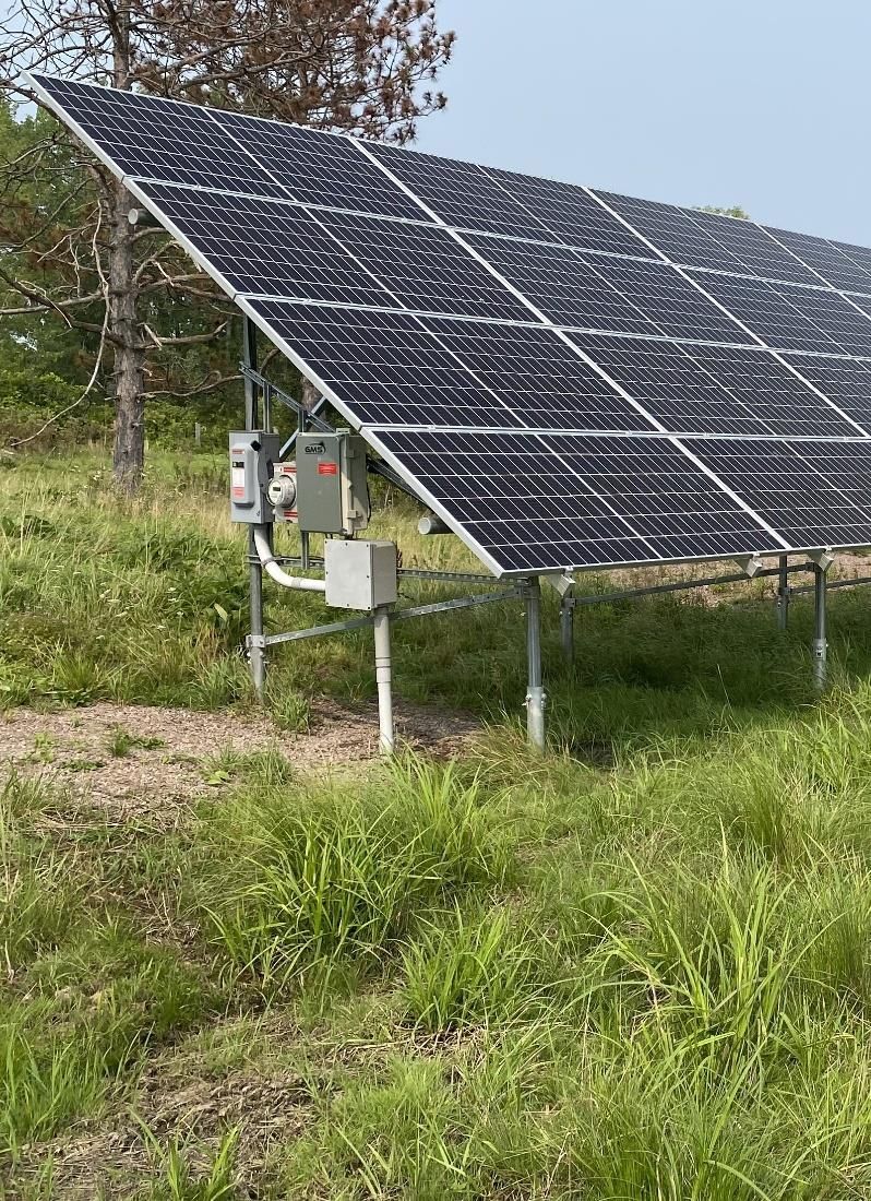 Ground-mounted solar panels in a grassy field, generating electricity.