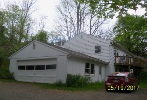 White house with attached garage and a red car parked nearby.