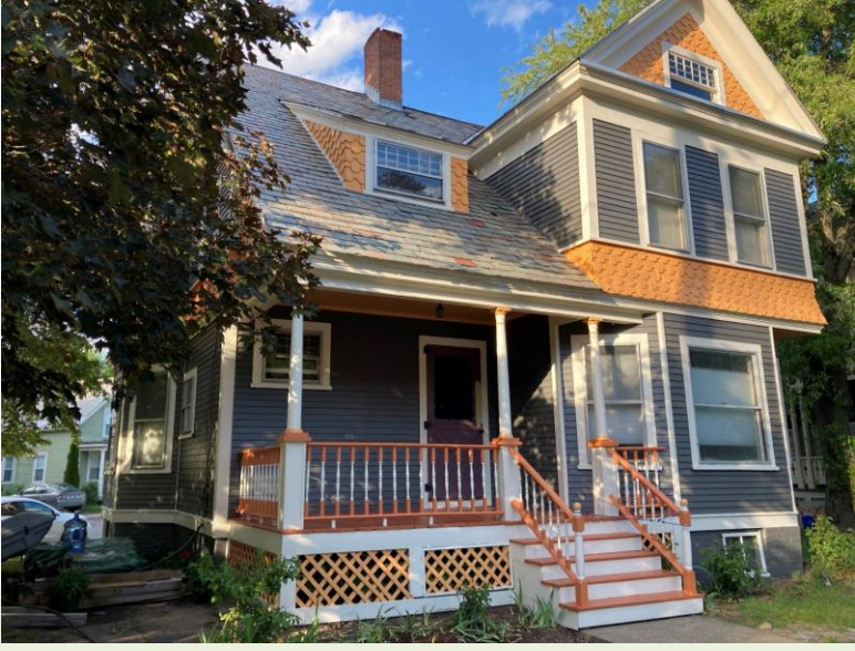 Two-story house with blue siding, orange trim, a porch, and stairs leading to the entrance.