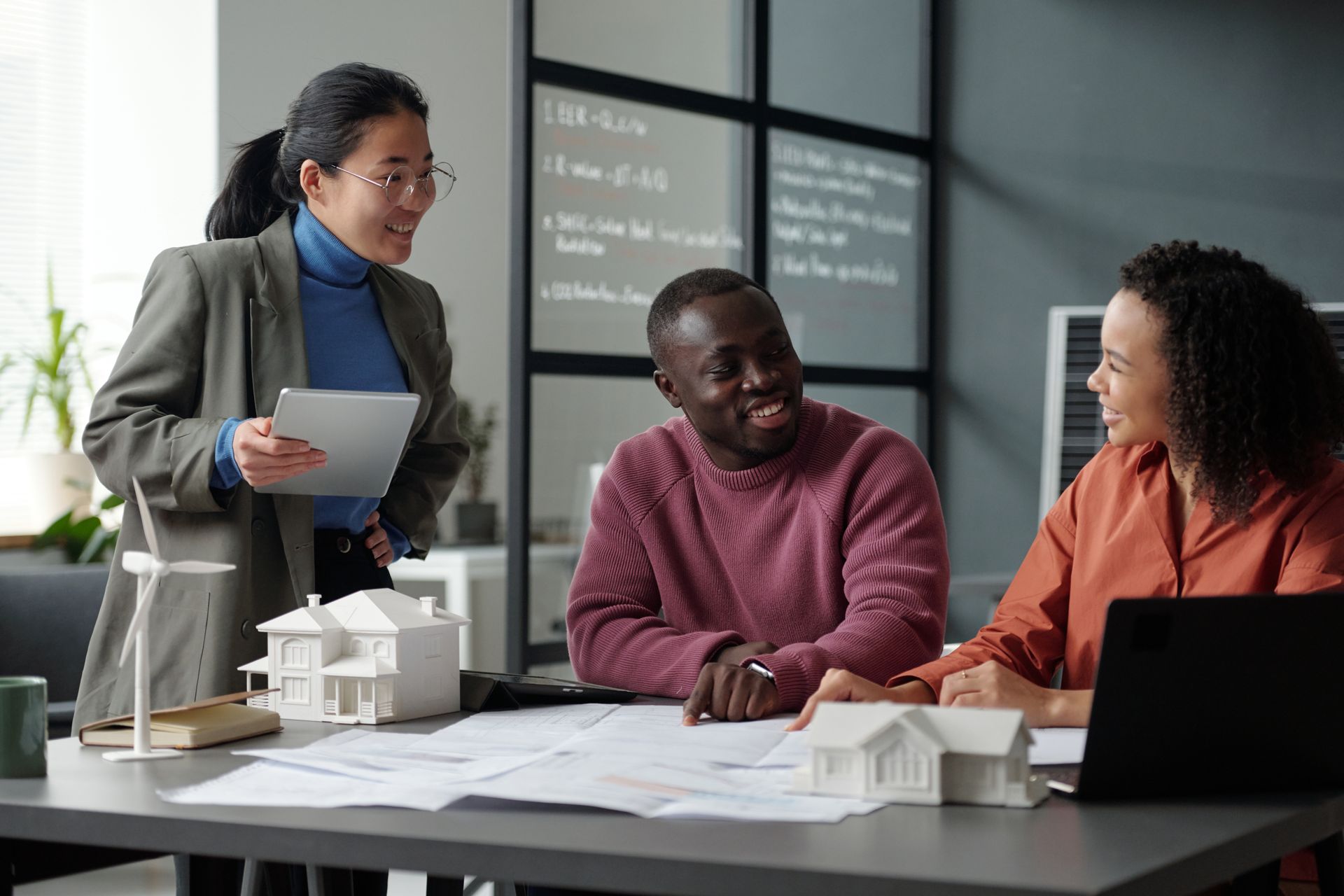 Three diverse people at a table, reviewing plans, discussing sustainable building.