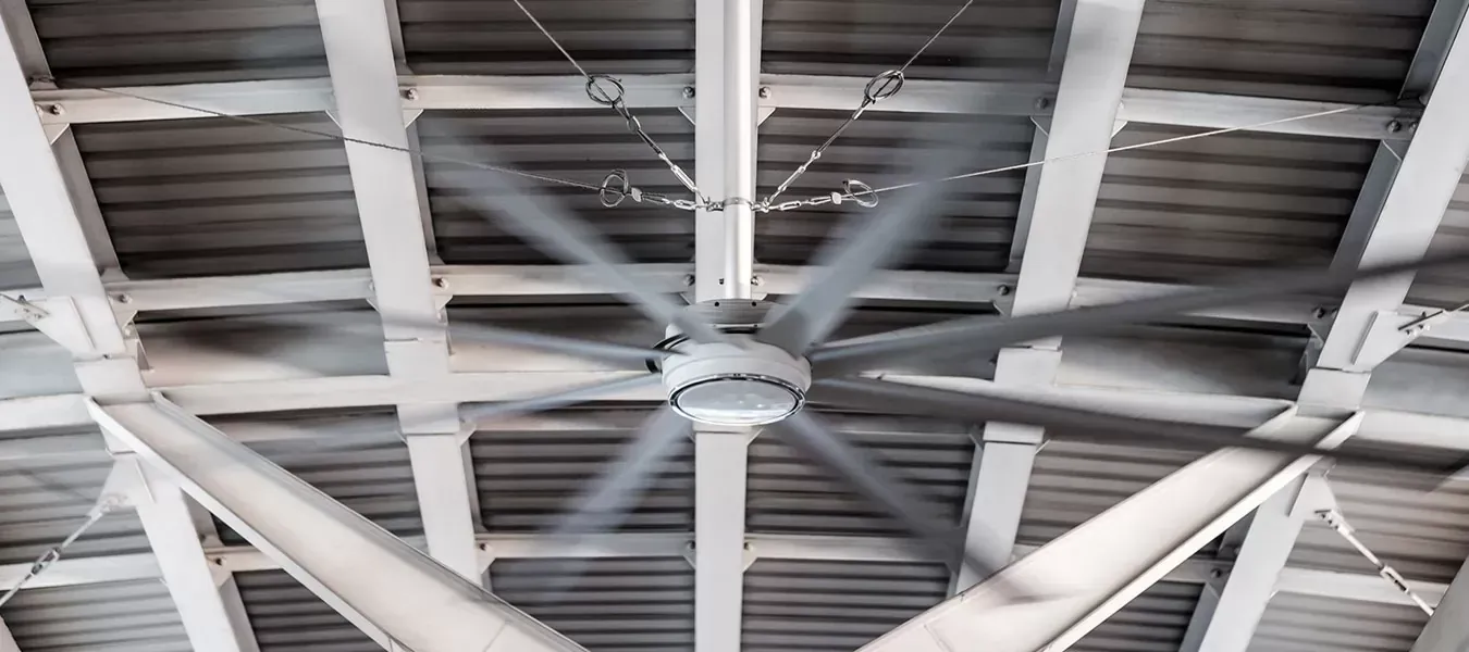 A large ceiling fan spins under a white-painted wooden roof structure.