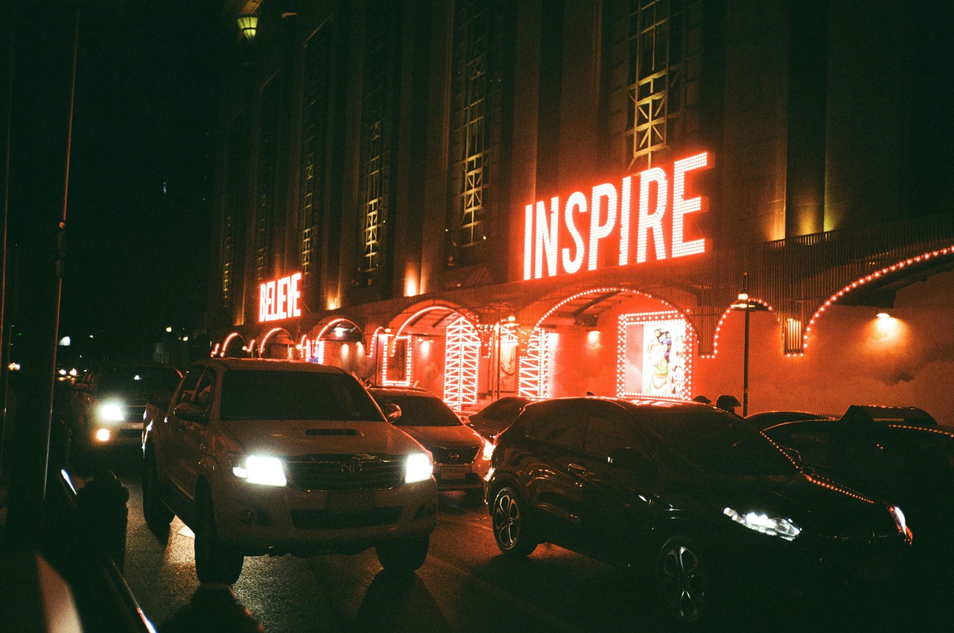 Cars are parked in front of a building that says inspire