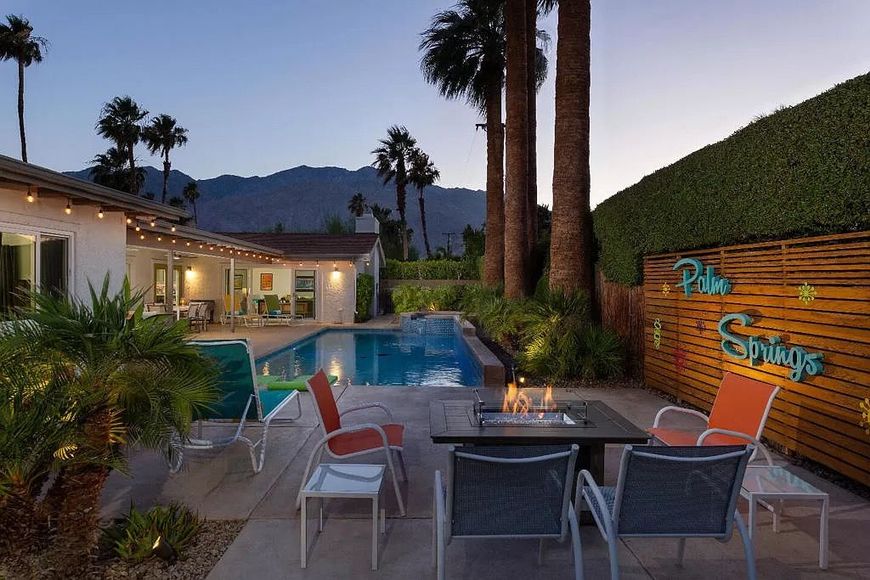 A patio with a table and chairs and a sign that says palm springs