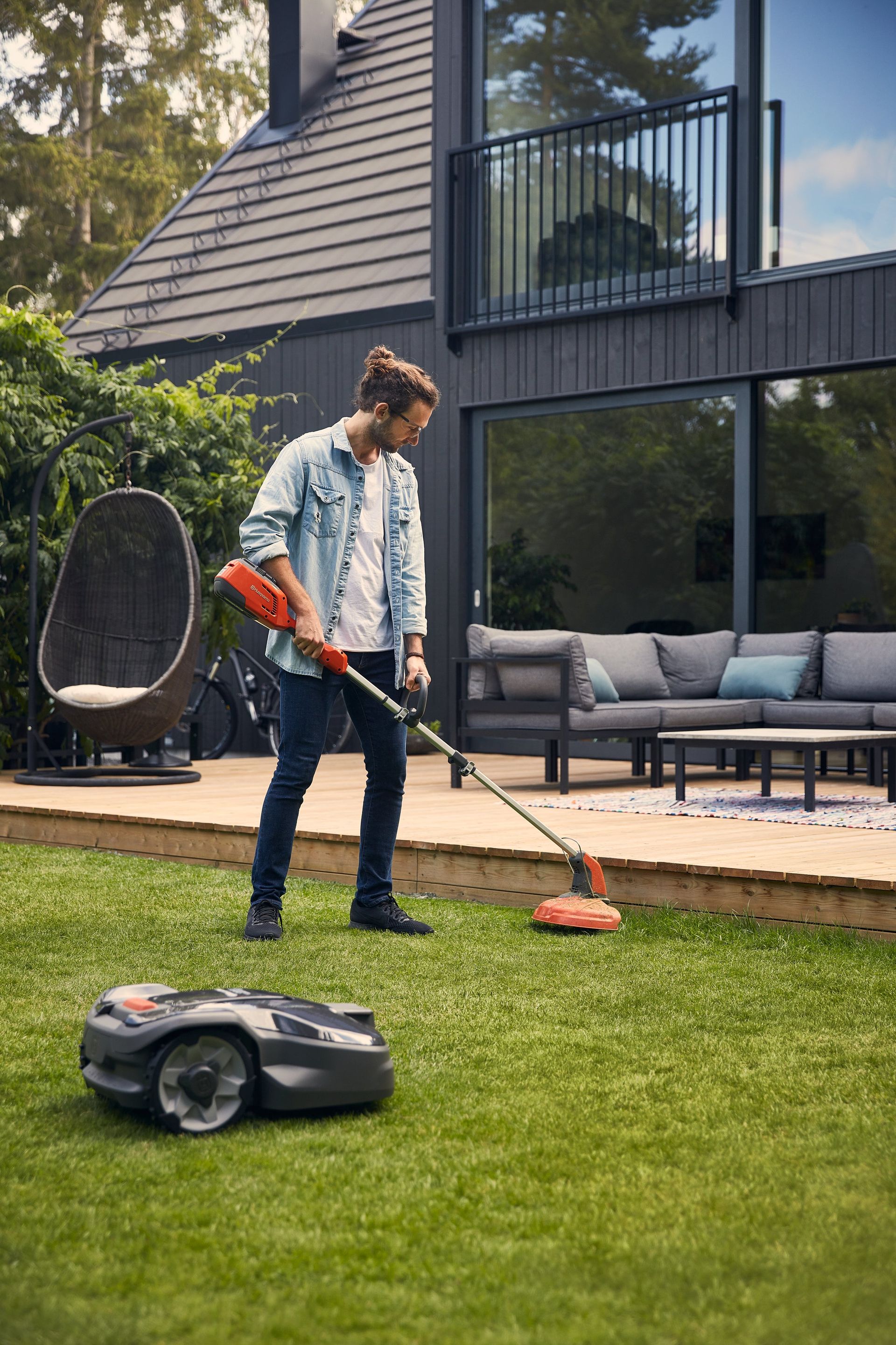 A Man Is Riding A Lawn Mower Through A Lush Green Field — Mid Coast Mowers In Taree, NSW
