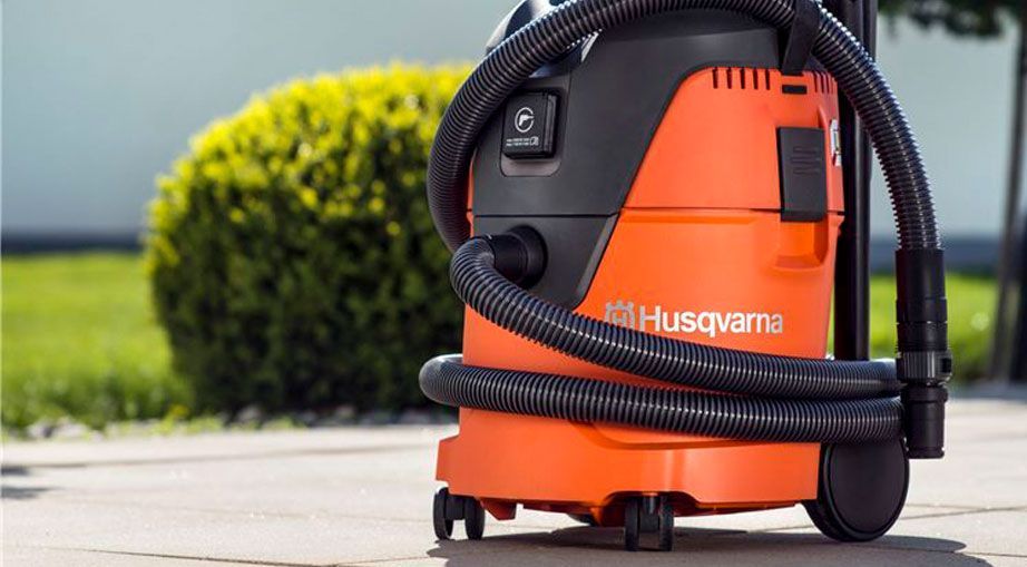 A Husqvarna Vacuum Cleaner Is Sitting on A Sidewalk Next to A Bush — Mid Coast Mowers In Taree, NSW