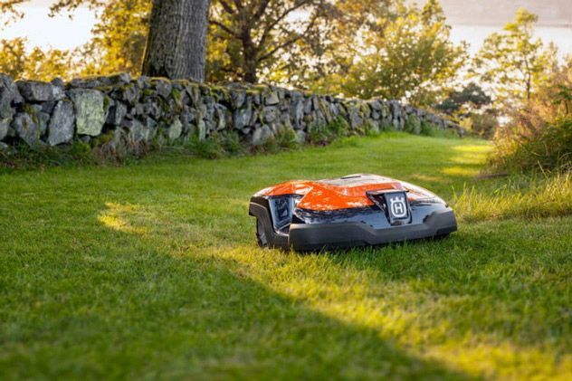 A Robotic Lawn Mower Is Sitting On Top Of A Lush Green Lawn — Mid Coast Mowers In Taree, NSW