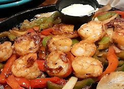 A close up of a plate of food with shrimp and vegetables on a table.