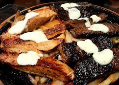 A close up of a plate of food with meat and sauce on a table.