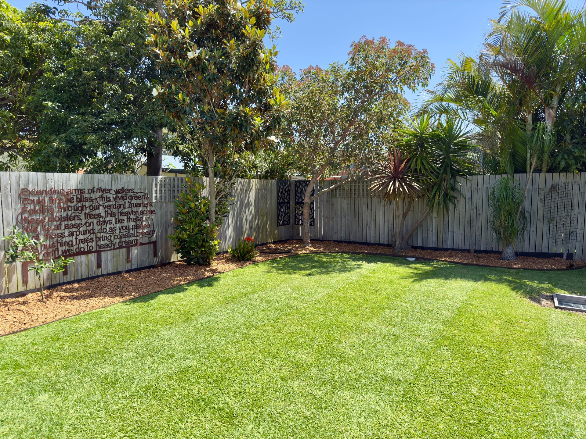 Green grass backyard with wooden fence and small trees — Mow & Mulch Lawn & Garden Maintenance In Medowie, NSW