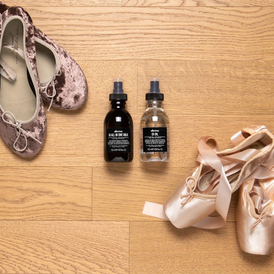 Ein Paar Ballettschuhe und zwei Parfümflaschen auf einem Holzboden