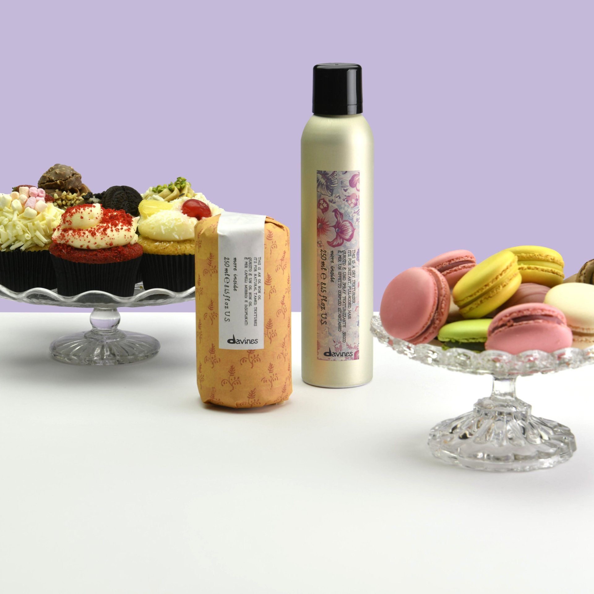 Eine Flasche Shampoo neben einem Teller mit Macarons und Cupcakes