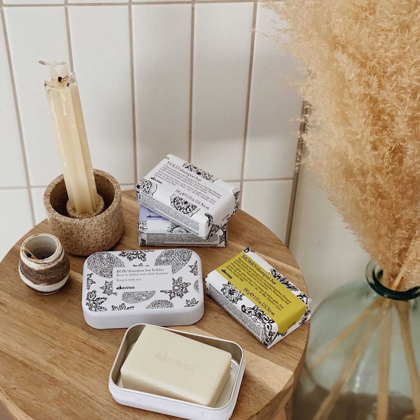 Ein Holzhocker mit Seife, Kerzen und einer Vase darauf