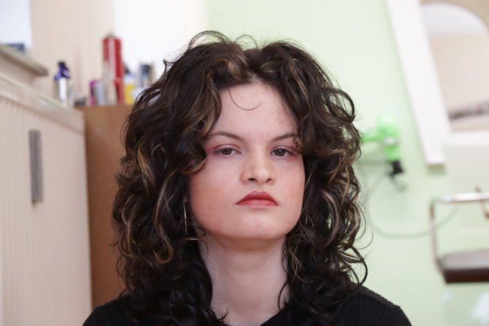 Eine Frau mit lockigem Haar trägt ein schwarzes Hemd