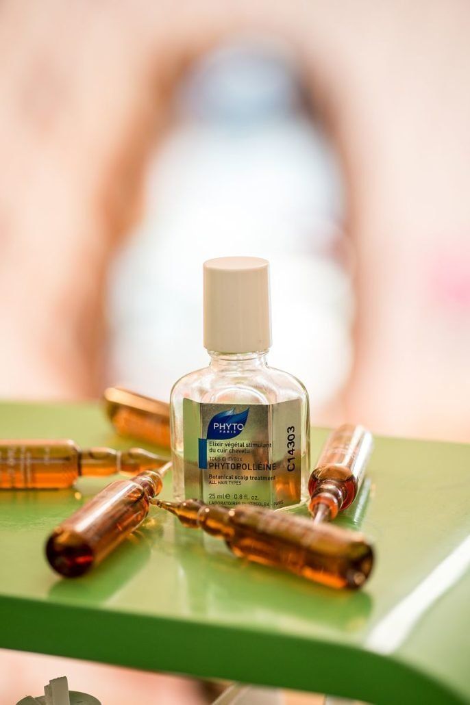 Eine Flasche Lotion steht neben einigen Ampullen auf einem grünen Tisch.