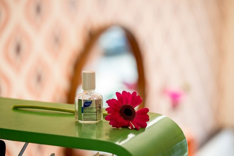 Eine Flasche Lotion und eine Blume stehen auf einem grünen Tisch.