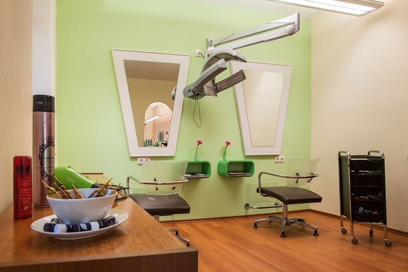 Ein Friseursalon mit einer grünen Wand und zwei Spiegeln