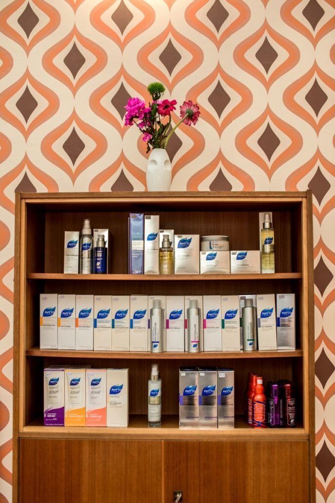 Ein Regal voller Schönheitsprodukte mit einer Vase mit Blumen darauf