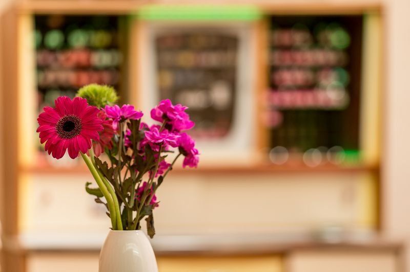 Auf einem Tisch steht eine Vase mit rosa Blumen.