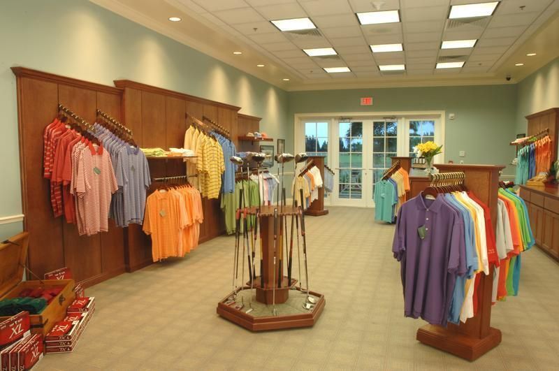 Golf apparel store interior with racks of colorful polo shirts and golf clubs on display.