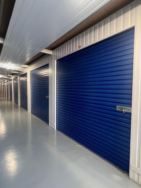 A row of blue garage doors are lined up in a hallway.