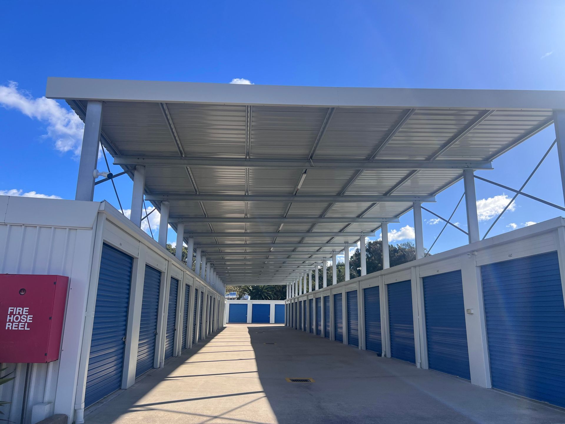 A row of blue and white storage units under a canopy.