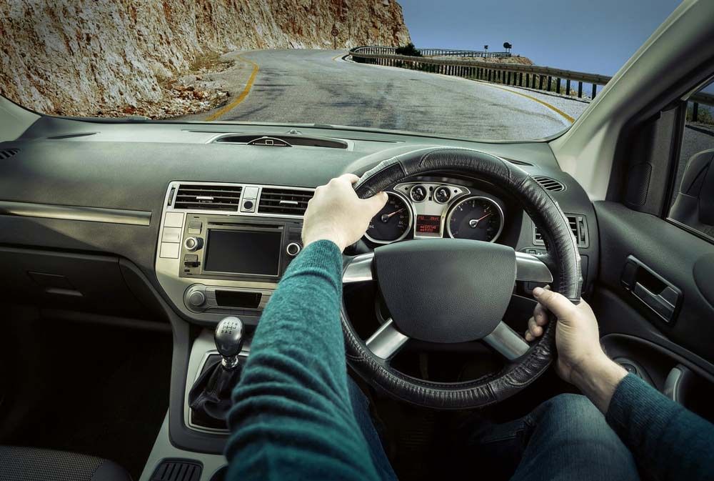 A Person is Driving a Car on a Mountain Road — Dave's Used Cars In Stuart, NT