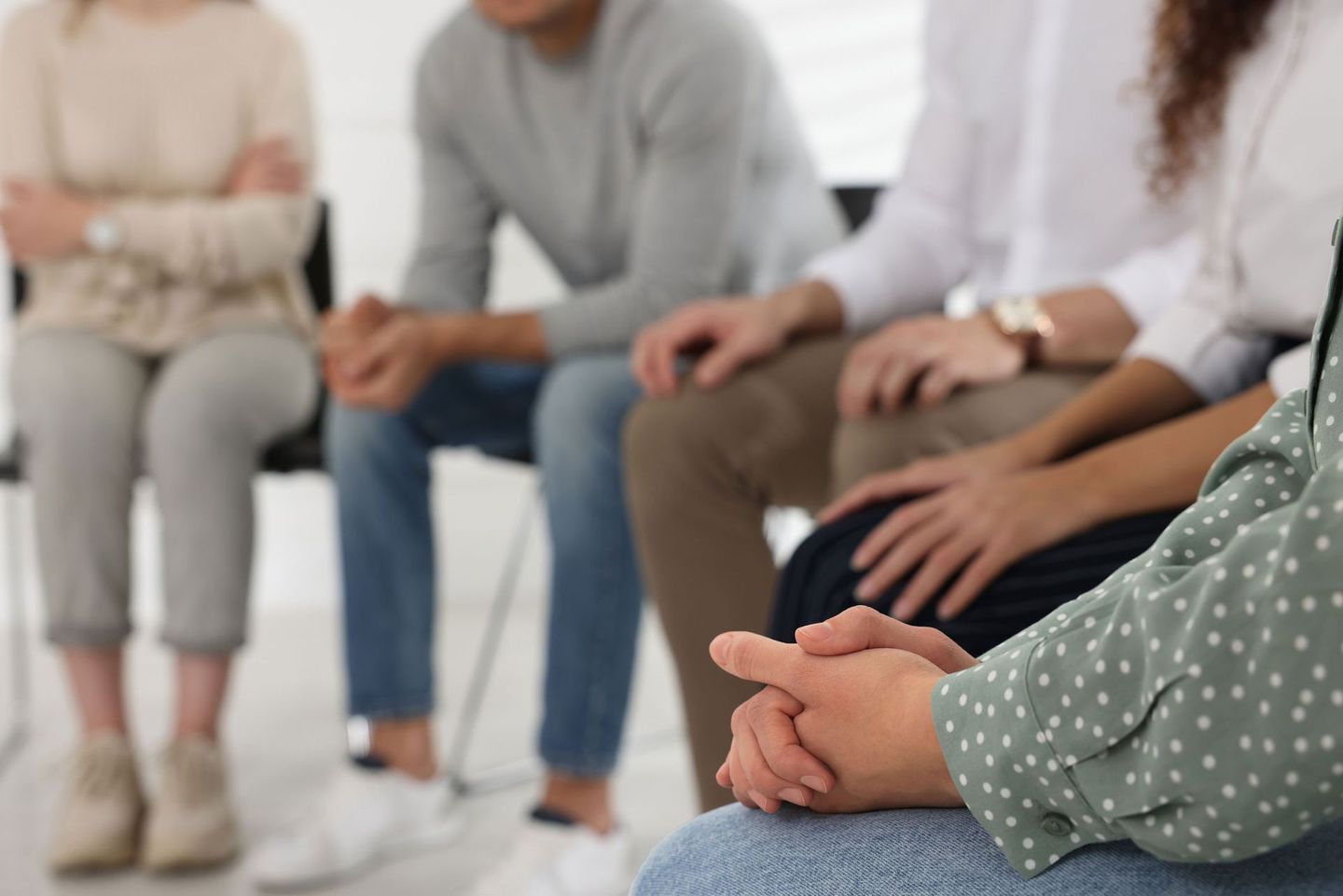 A group of people are sitting in a circle with their hands folded.