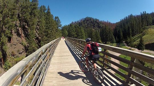 A person is riding a bike on a wooden bridge.