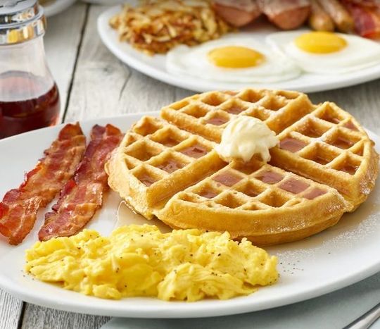 A waffle with bacon and scrambled eggs on a plate