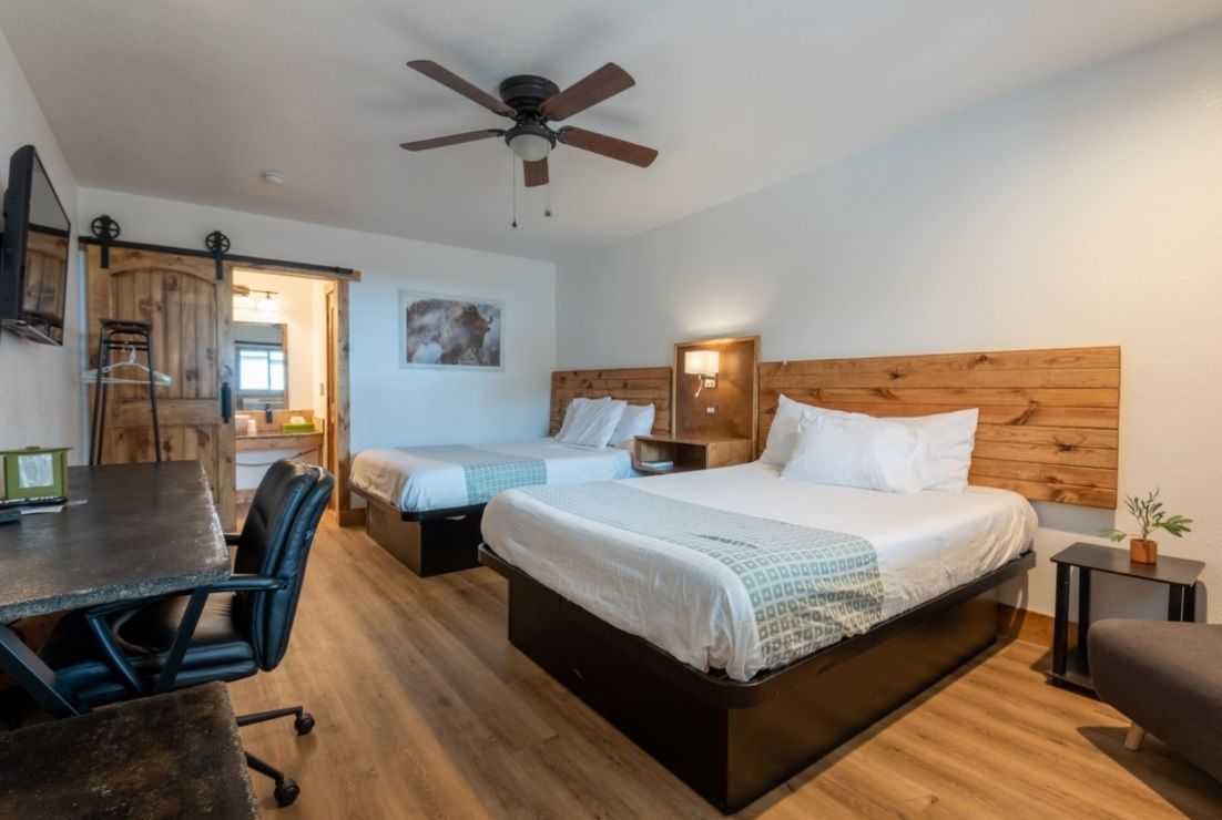 A hotel room with two beds , a desk and a television.