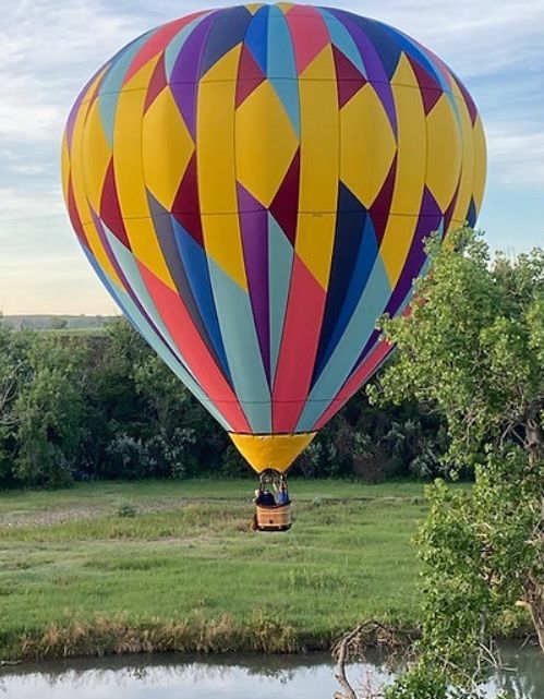 An old car is parked in front of a log cabin