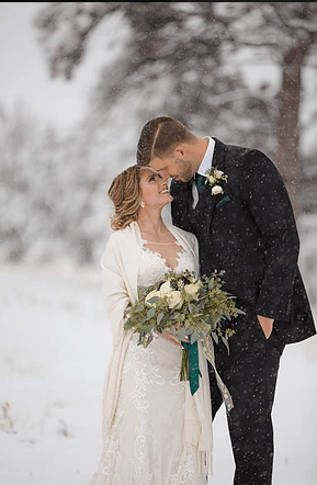 A bride and groom are kissing in the snow.
