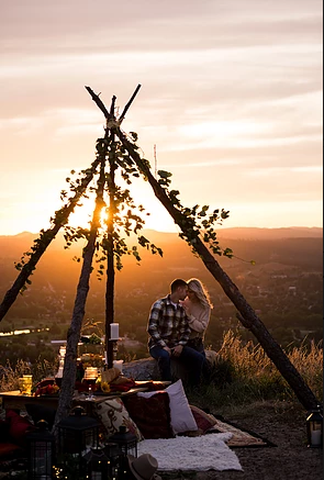 A man and a woman are sitting in a teepee at sunset.