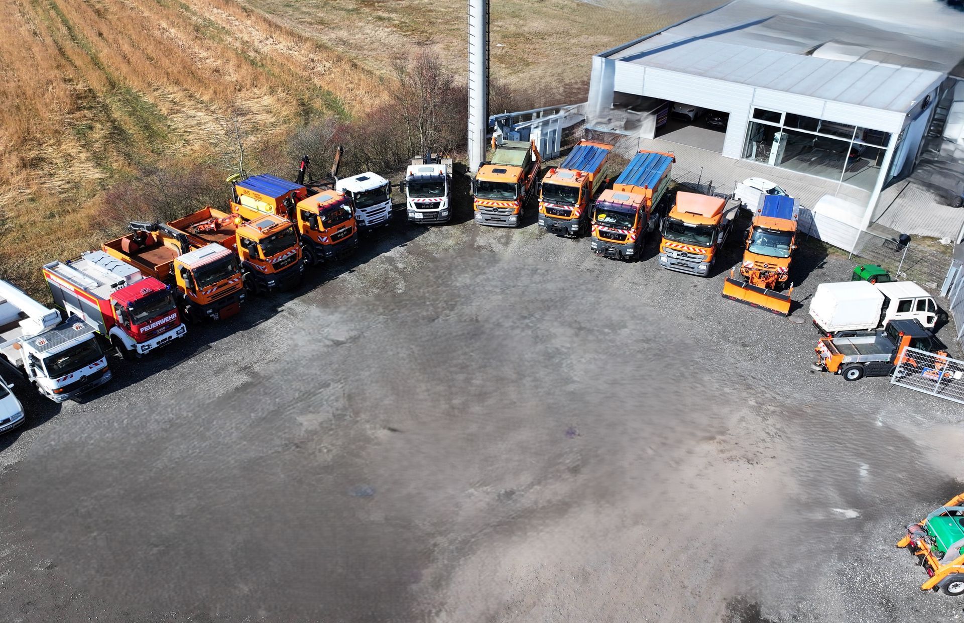 Widok z lotu ptaka na szereg ciężarówek zaparkowanych przed budynkiem.