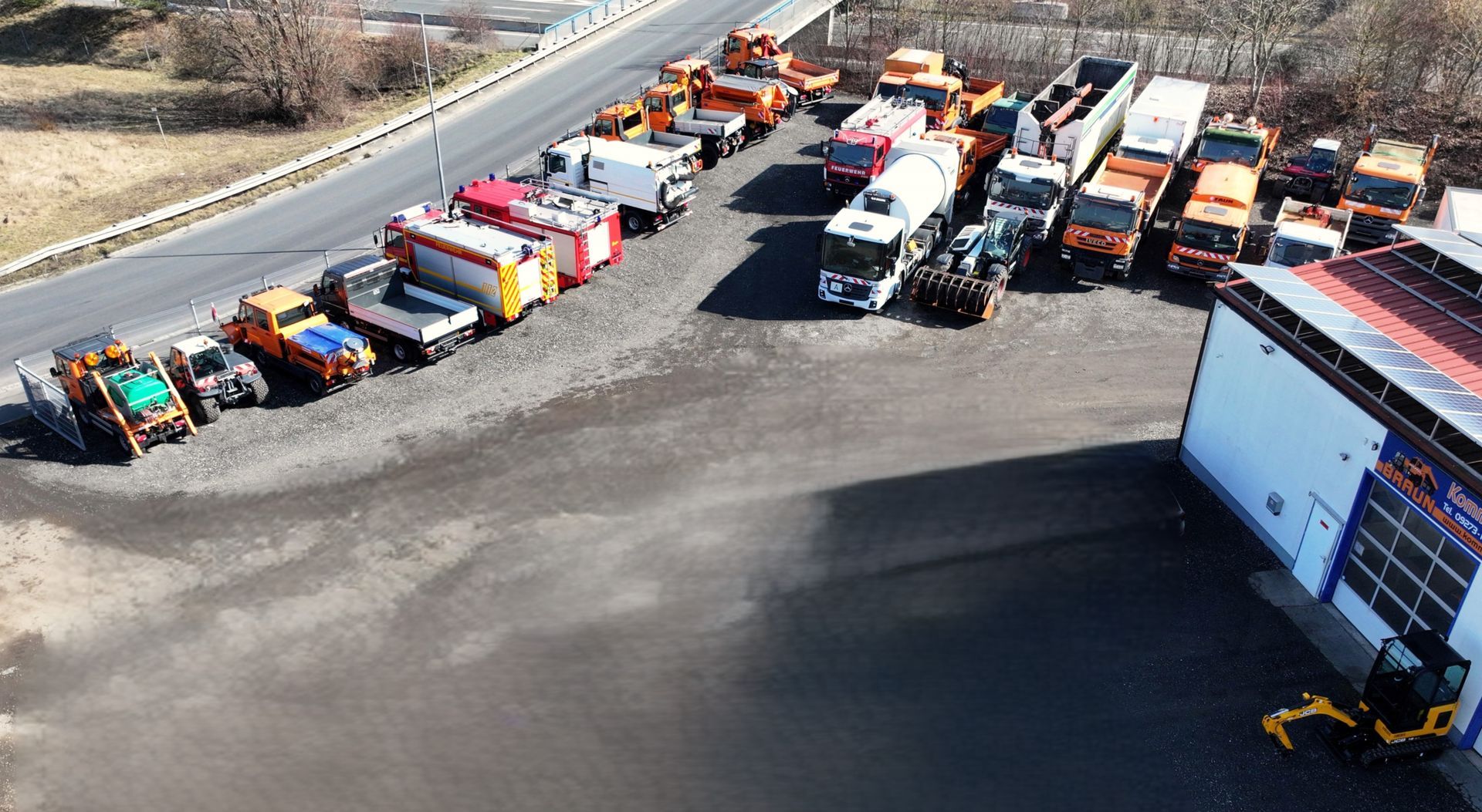 Szereg ciężarówek zaparkowanych na parkingu przy drodze.