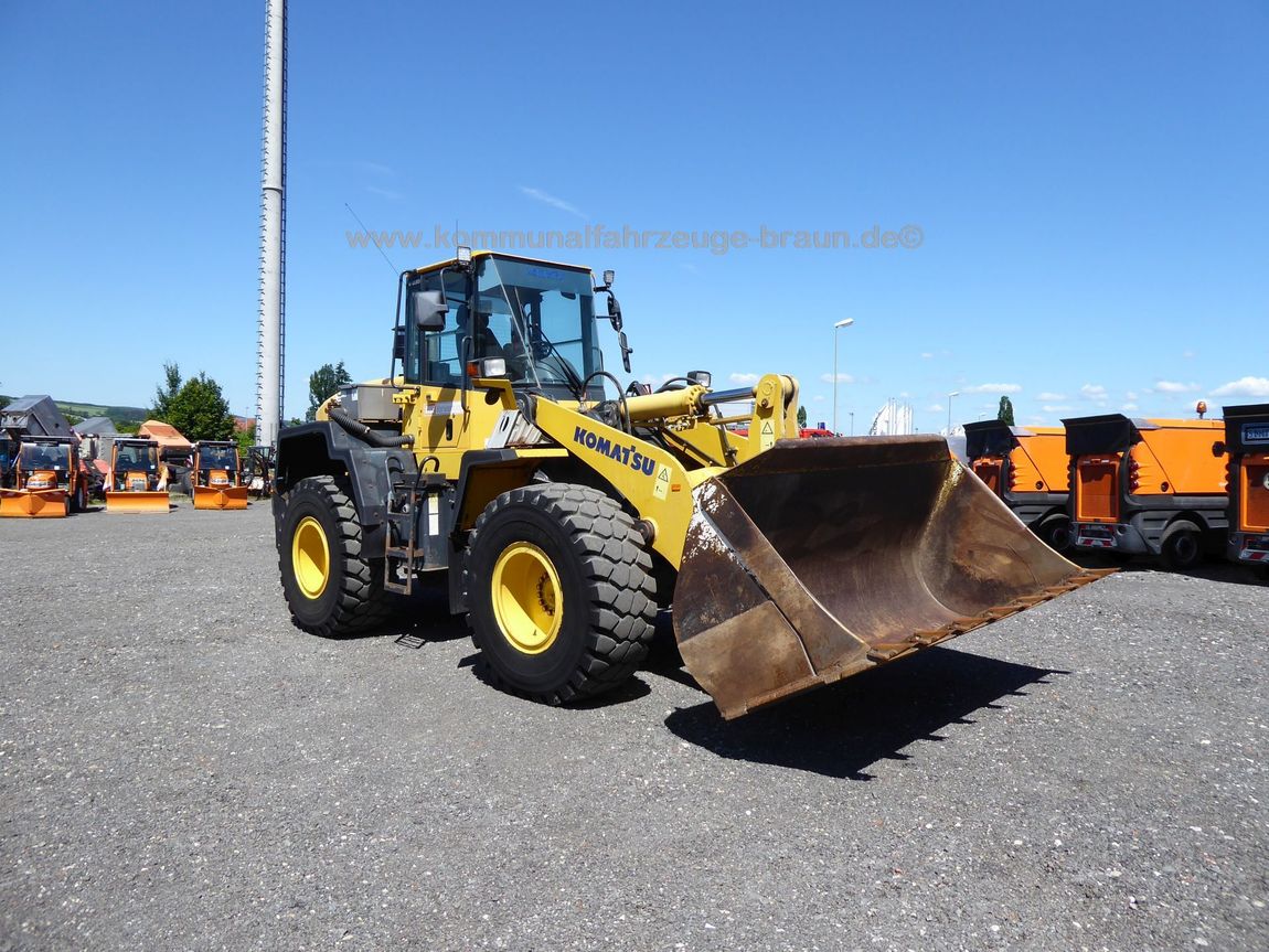 Ein gelb-schwarzer Komatsu-Radlader steht auf einem Schotterplatz.