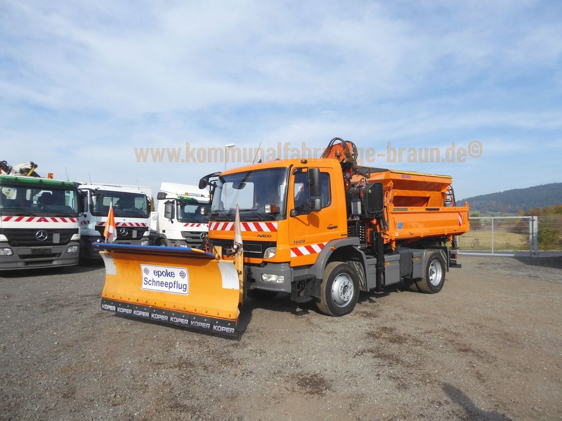 Ein orangefarbener LKW mit einem daran befestigten Schneepflug