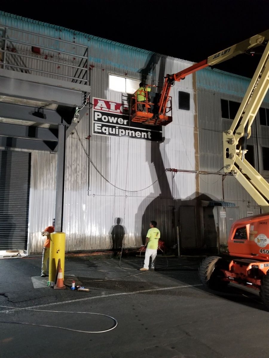 A man is using a crane to remove a sign from the side of a building.