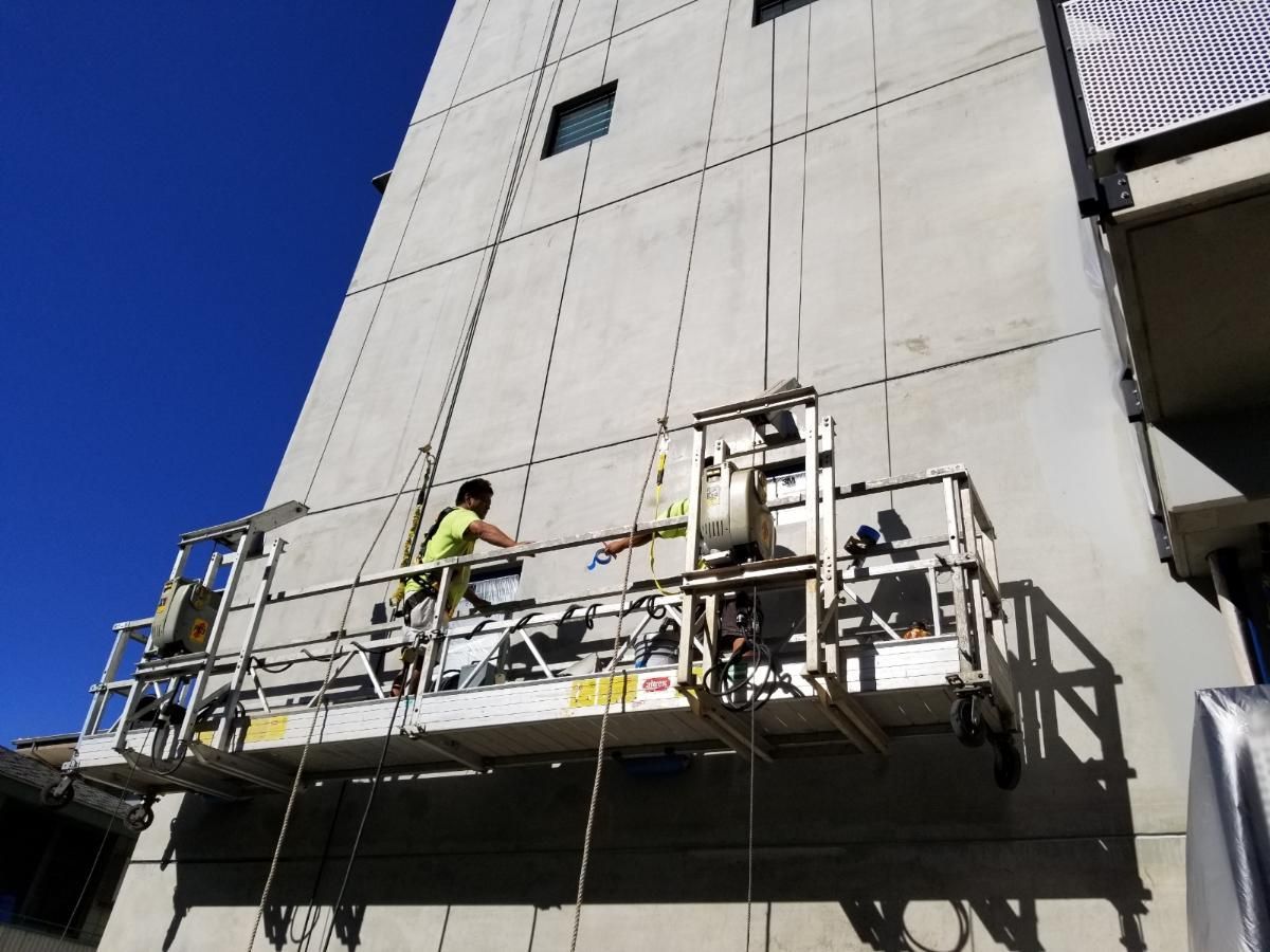 A man is working on the side of a building on a scaffolding.