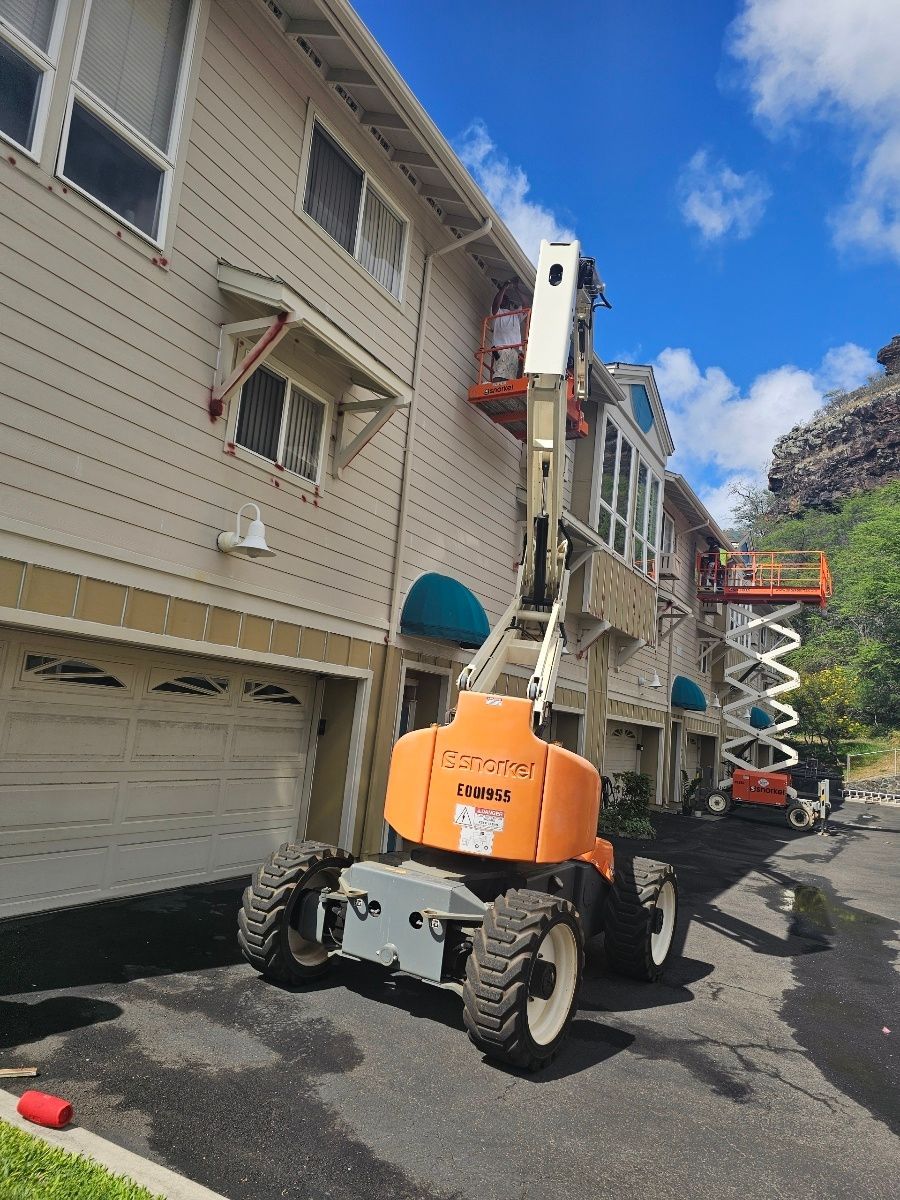A crane is being used to paint the side of a building.