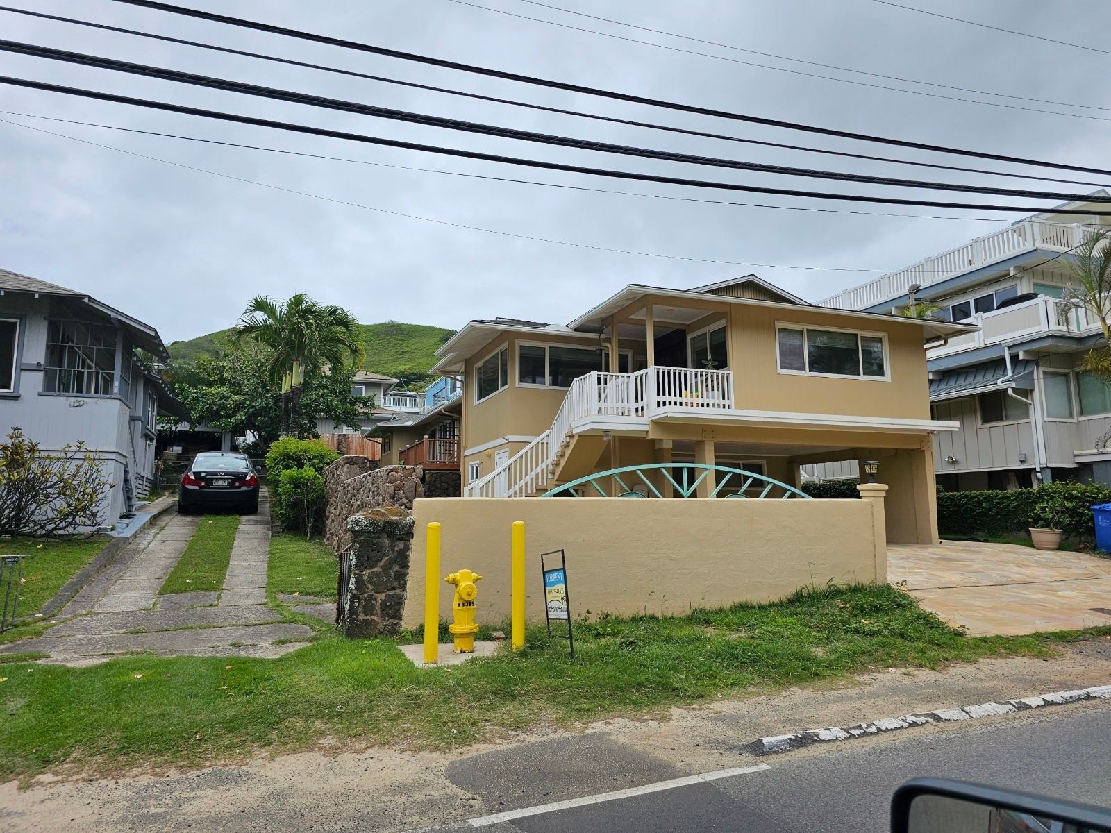 A house with a car parked in front of it and a fire hydrant in front of it.