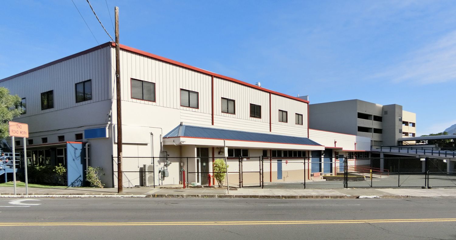 A large white building with a red roof is sitting on the side of the road.