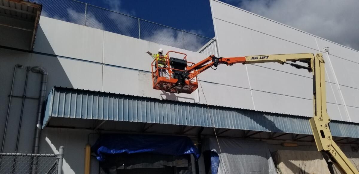 A man is working on the side of a building with a crane.