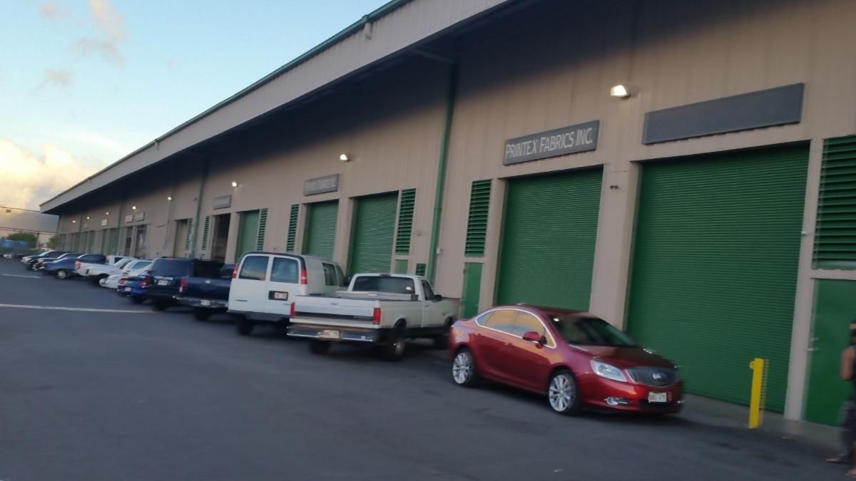 A row of cars are parked in front of a building with green doors.