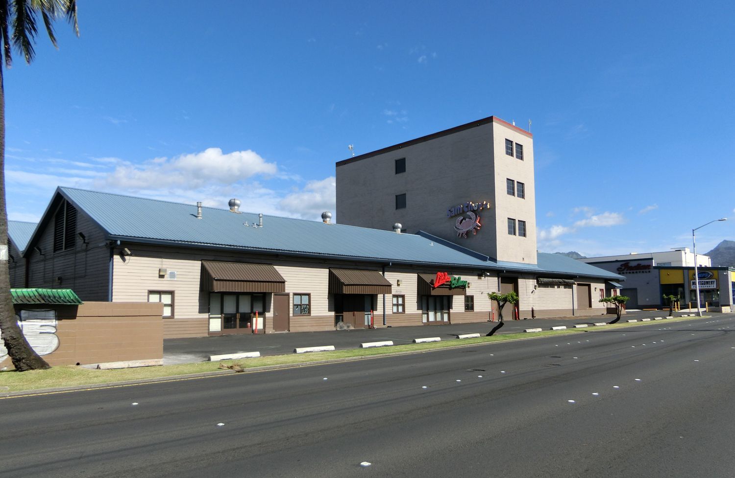 A large building with a blue roof is on the side of the road.