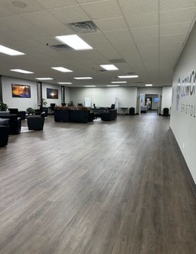 An empty lobby with dark gray wood flooring, seating, and a few decorations.