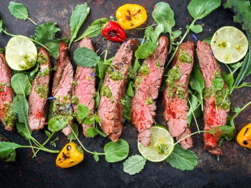 Eine Nahaufnahme eines Tellers mit Fleisch und Gemüse auf einem Tisch.